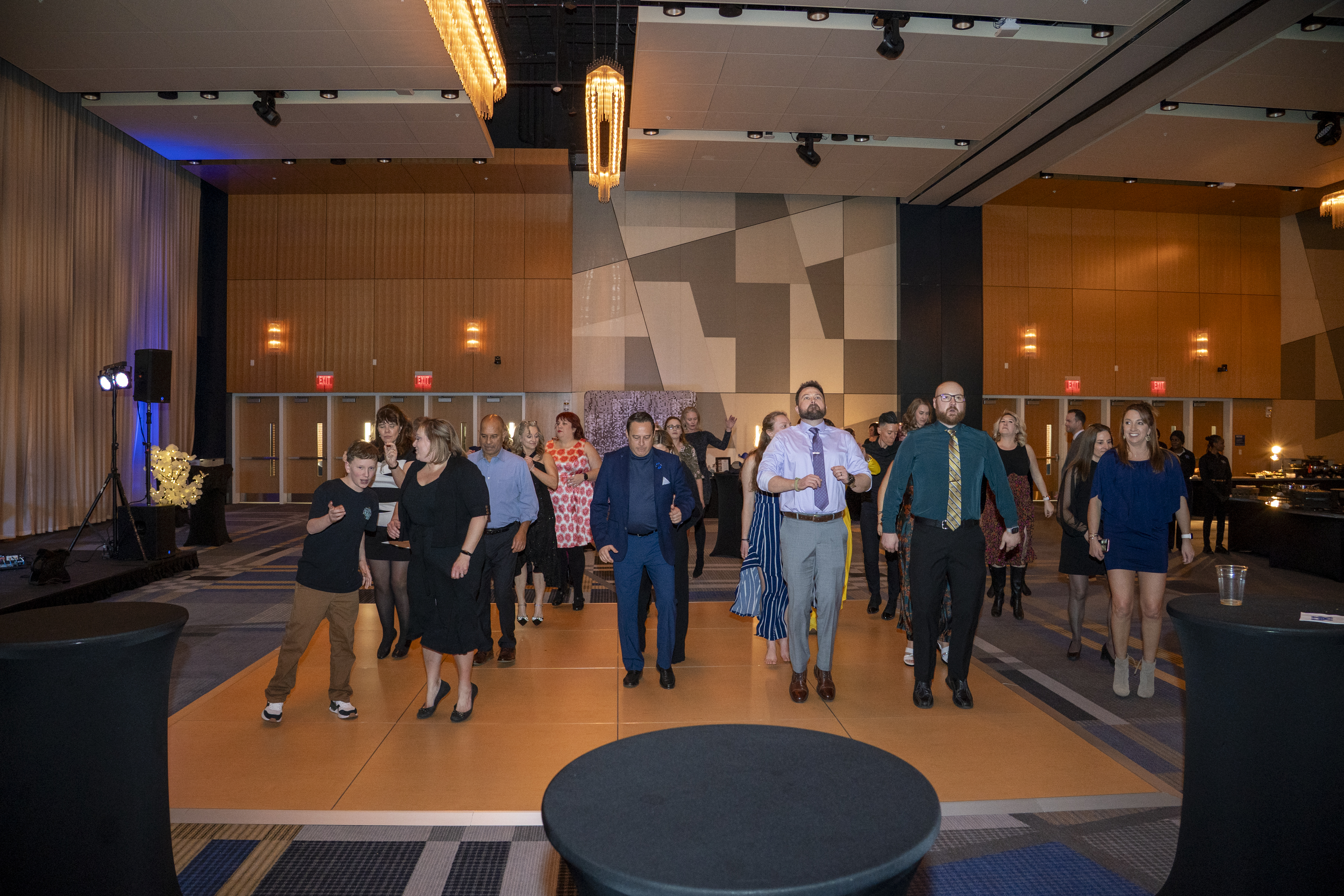 Folks on the dance floor all face forward and appear to be jumping in rhythm 