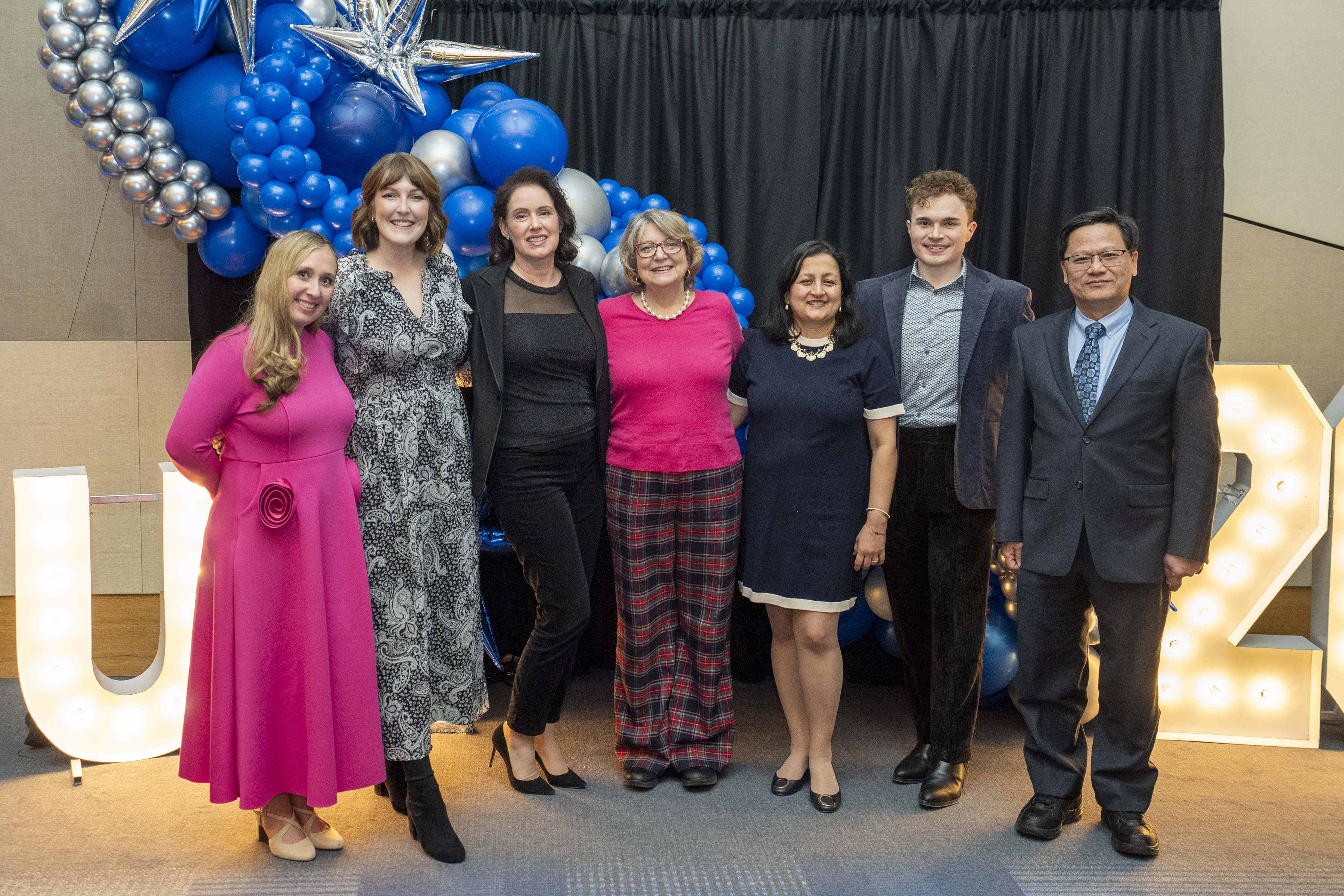 The infectious diseases division stands in formal attire in front of a balloon wall