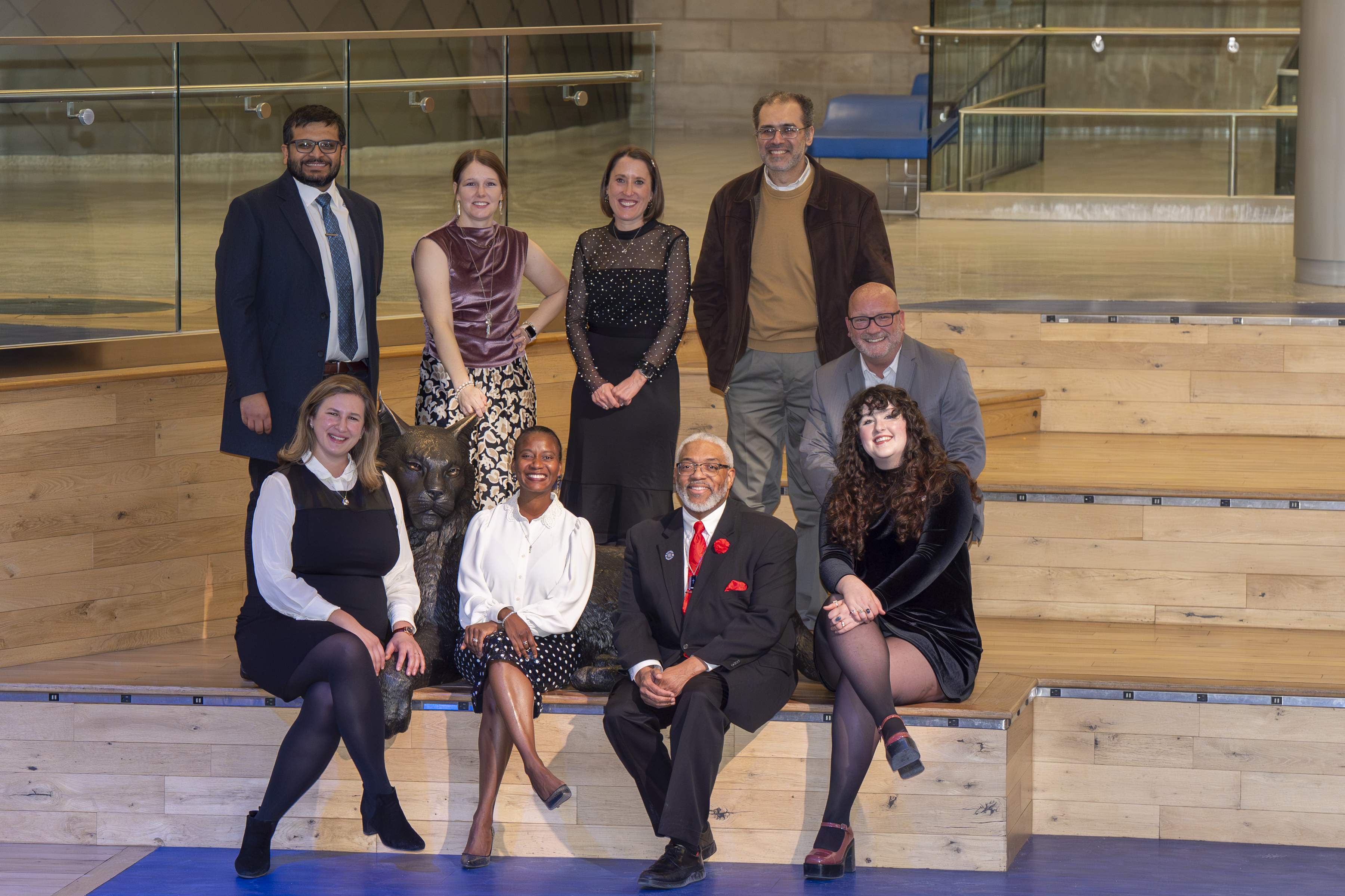 A group of people post for a photo on large wooden steps in formal attire