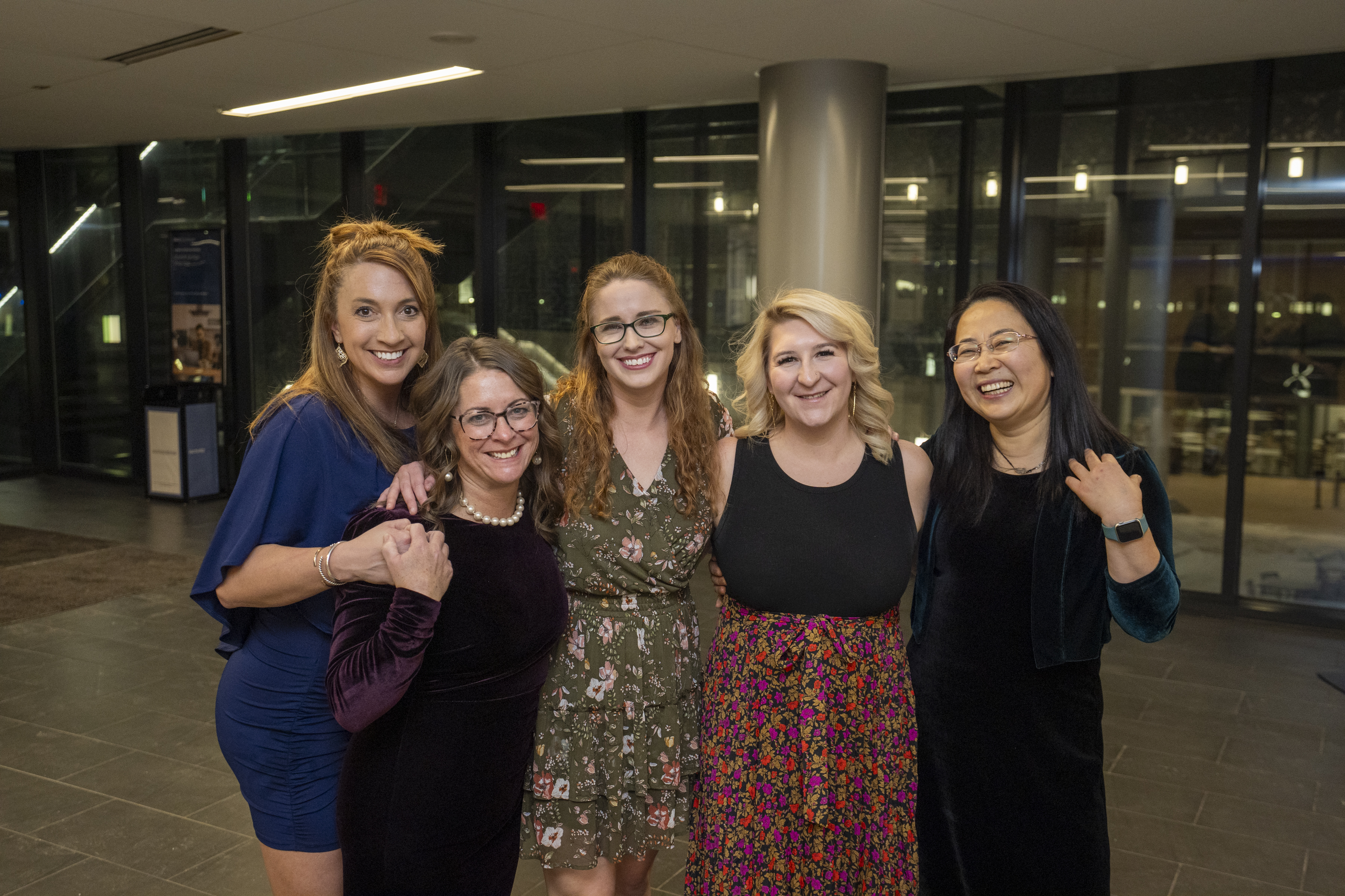 A group of women pose for a photo in formal attire