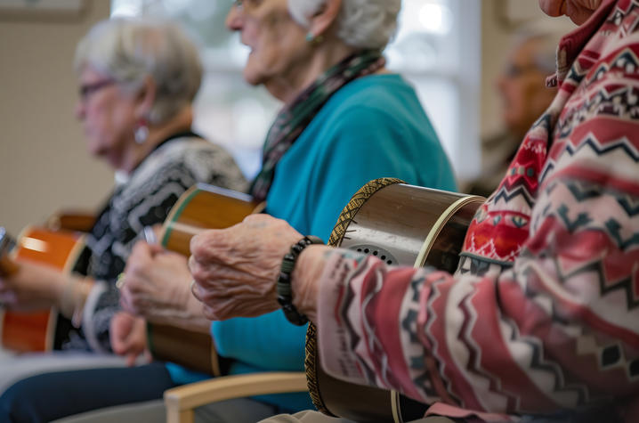 A line of three elderly women sitting together, holding musical instruments.