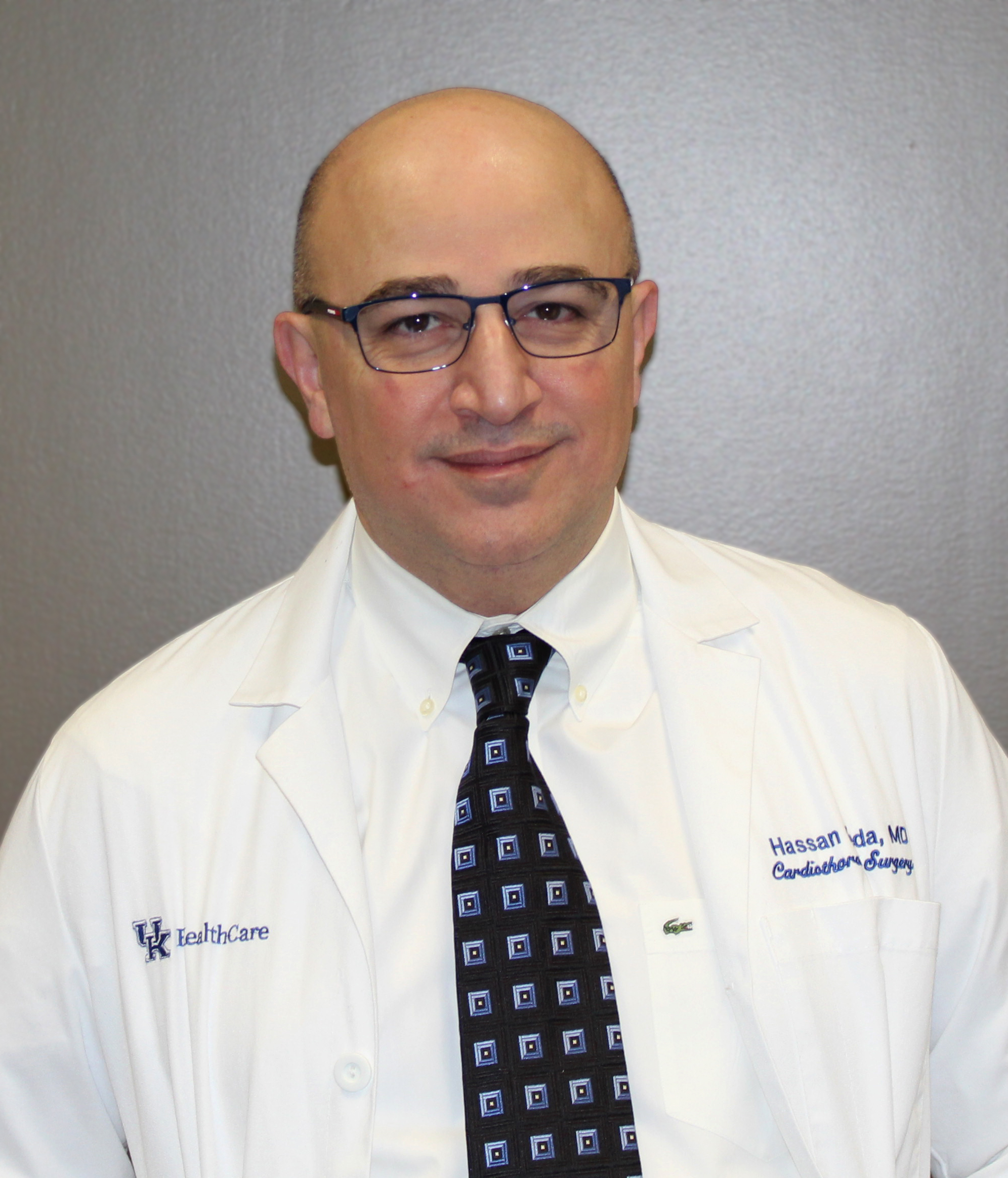 Headshot of Dr. Hassan Reda wearing a white coat and tie in front of a gray background