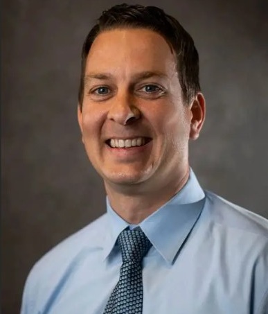 smiling man in a light blue dress shirt and blue necktie