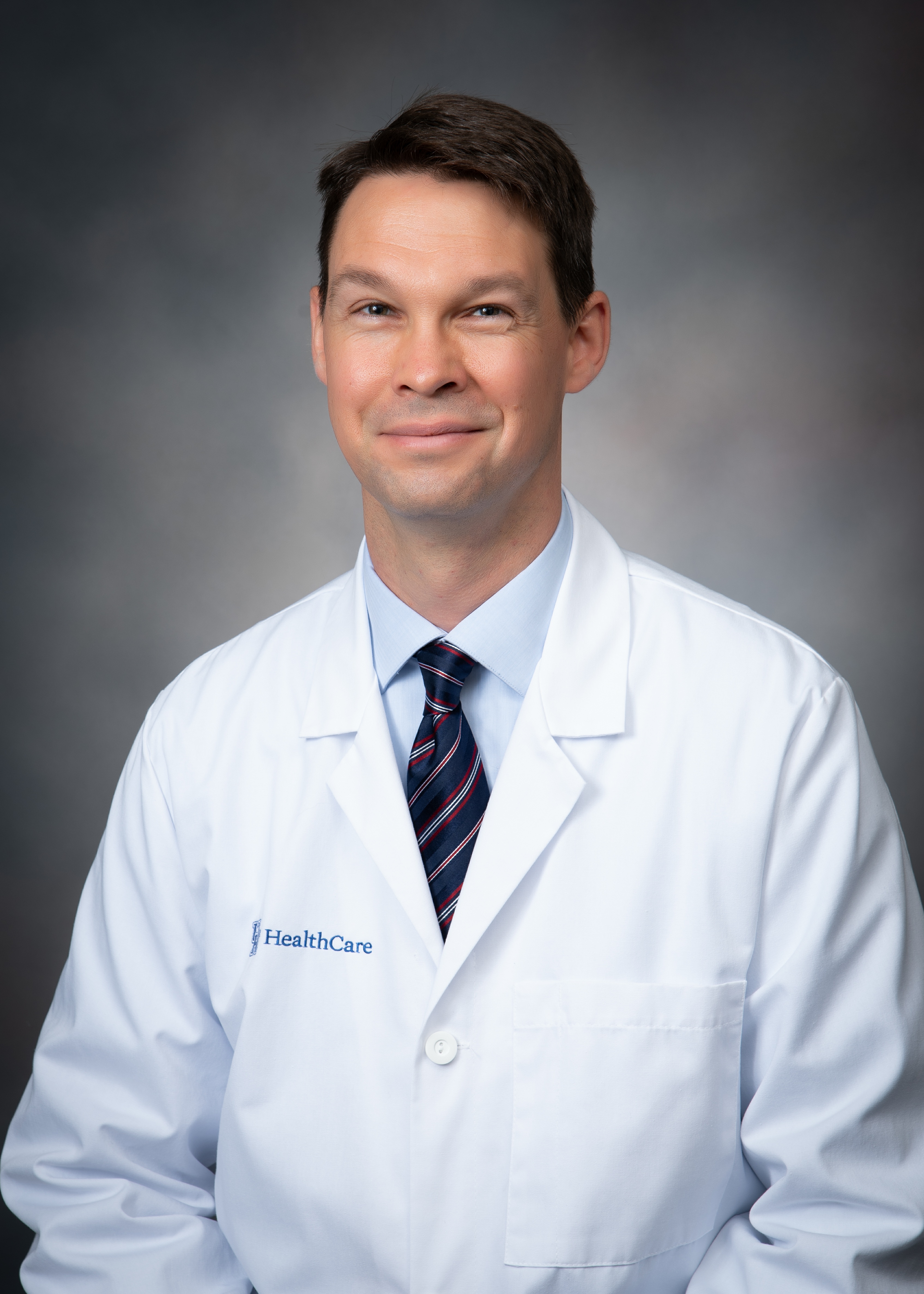 Dr. Michael Powers smiles for a headshot in his white coat