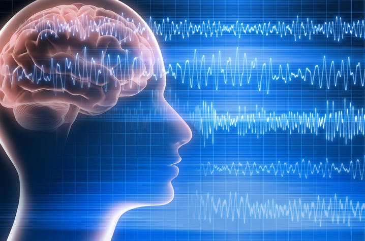 A graphic of the human brain within a silhouette of the human head. Brain waves overlap and travel from left to right of the image.