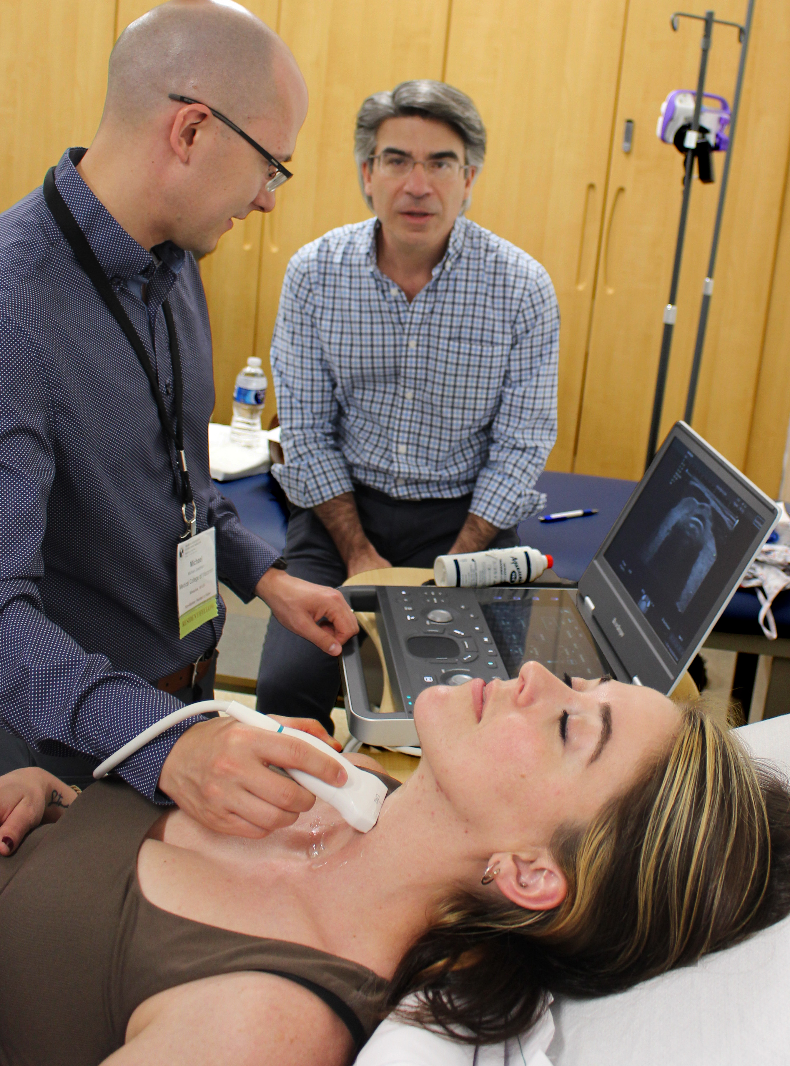 Endocrine fellow uses ultrasound equipment on a volunteer while being coached by a trainer during simulation training.