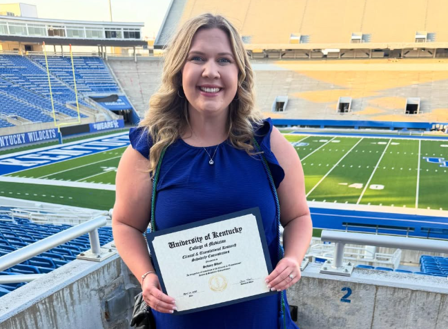 Sydney Short poses with certificate above Kroger field. 
