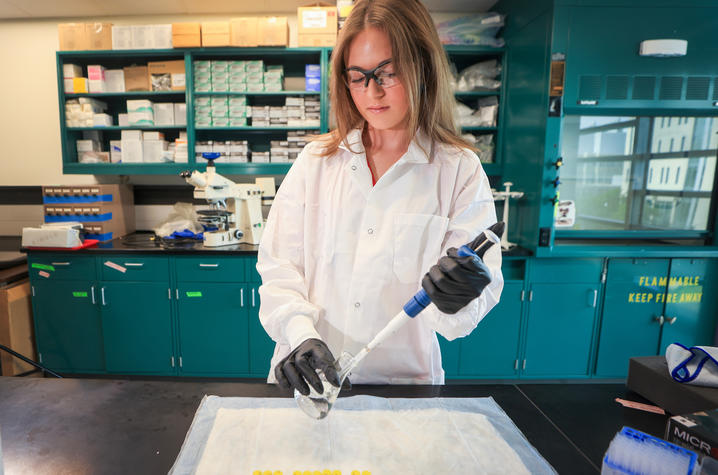 McKenna Green using a pipette and beaker in the laboratory.