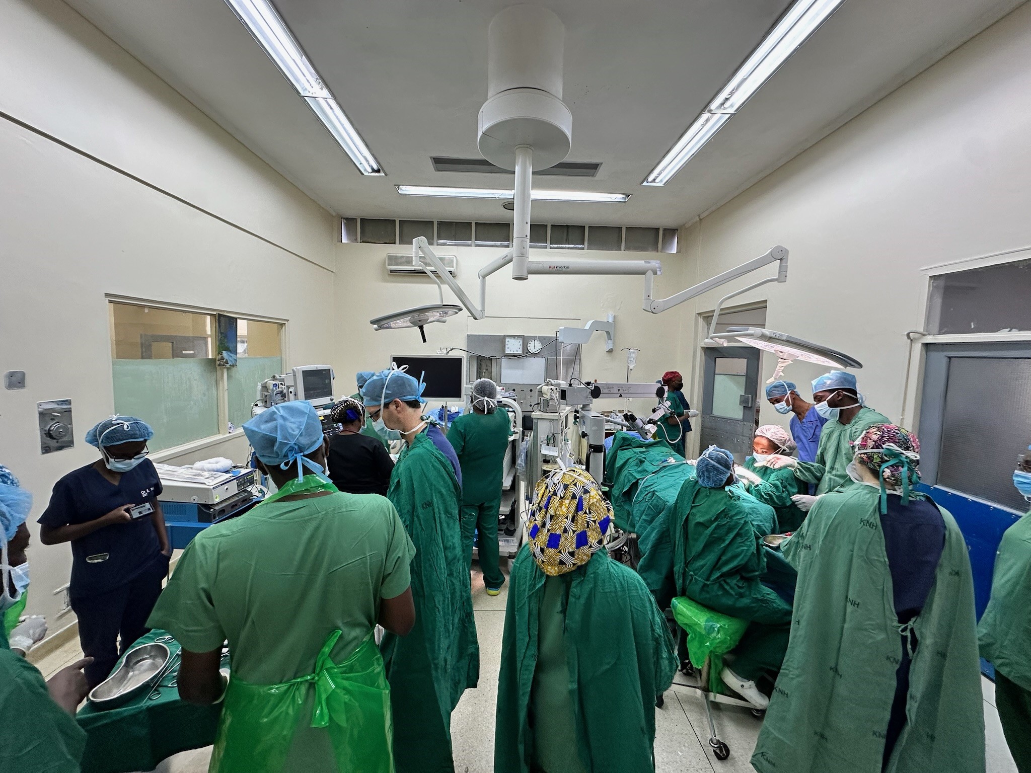 A wide shot picture of multiple people working in an OR in East Africa. 