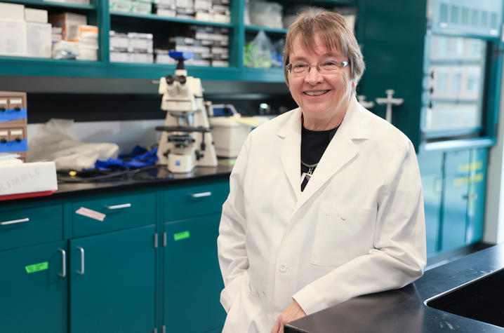 Linda Van Eldik, Ph.D. in her laboratory, wearing her white coat.