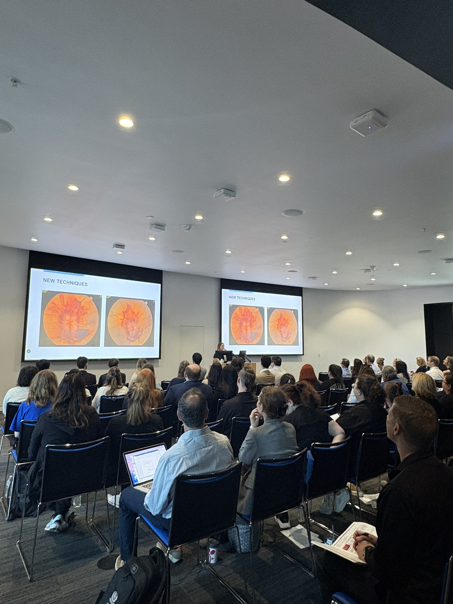 Audience view of Resident Research Day showcasing several people sitting in an room looking at the presenters screen