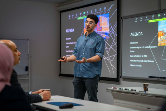 Azzam standing at the front of a classroom teaching a course