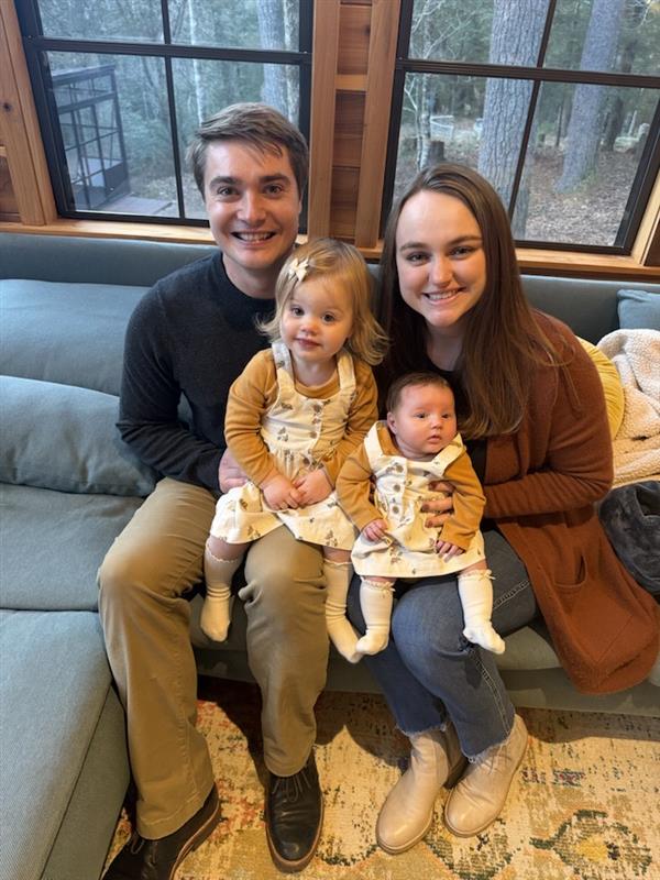 Elizabeth sitting with her husband and two children in their lap smiling at the camera.