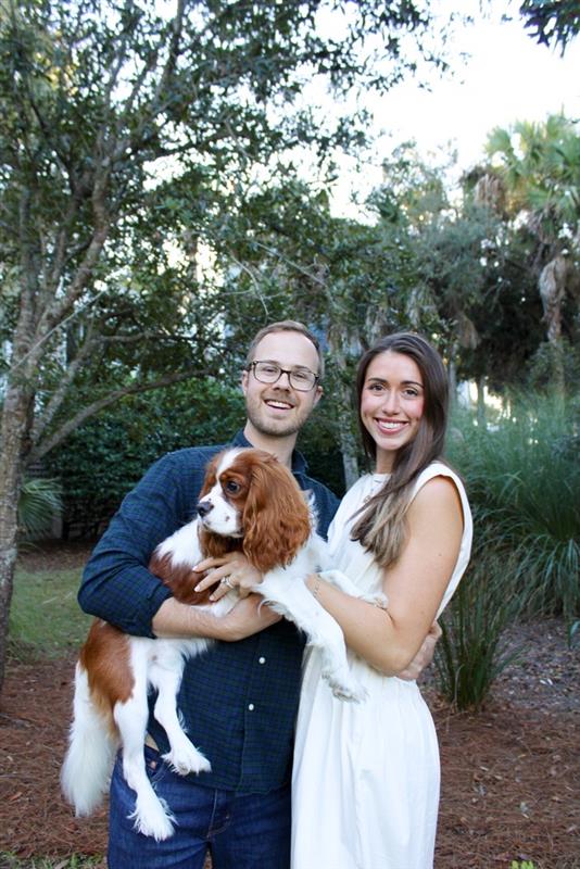 Adam Snowden and His wife smiling while holding their dog outside