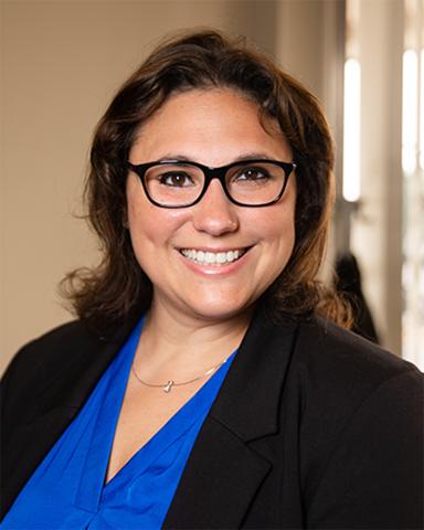 Dr. Elizabeth Rhodus, a brunette woman in glasses smiling, wearing a blue blouse under black blazer. 