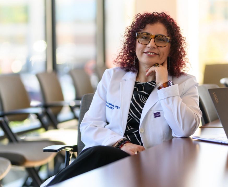 Dr. Pinar Coskun seated at table with sunlight streaming in