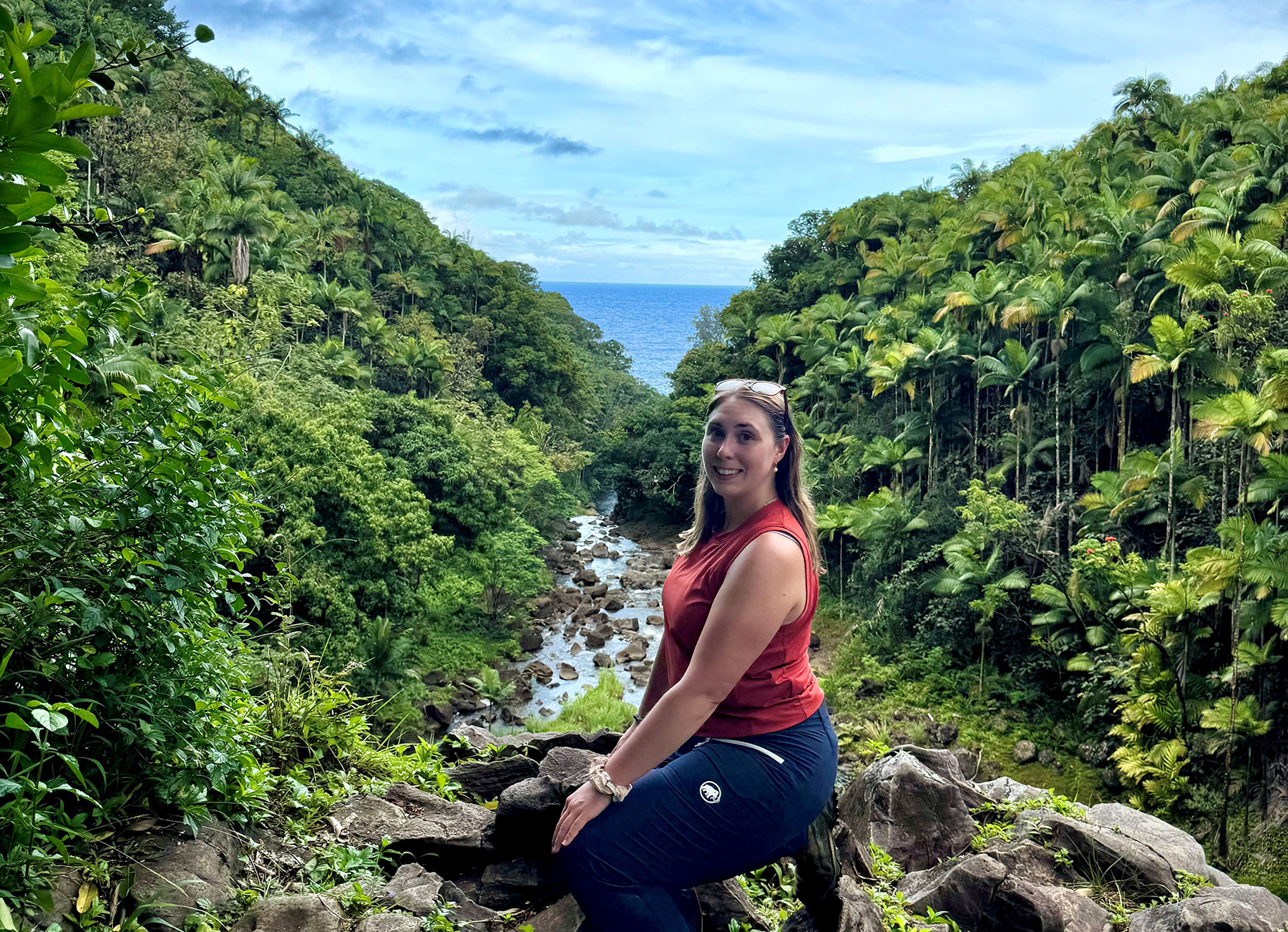 Lacey Burke kneeling by a river on a hike in Hawaii.