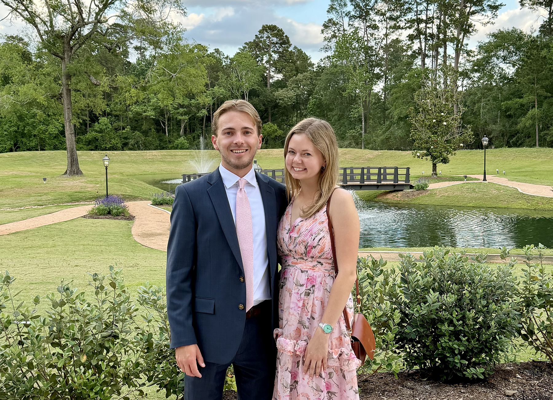 Anna Claire Taylor and her date standing in front of a manicured landscape.