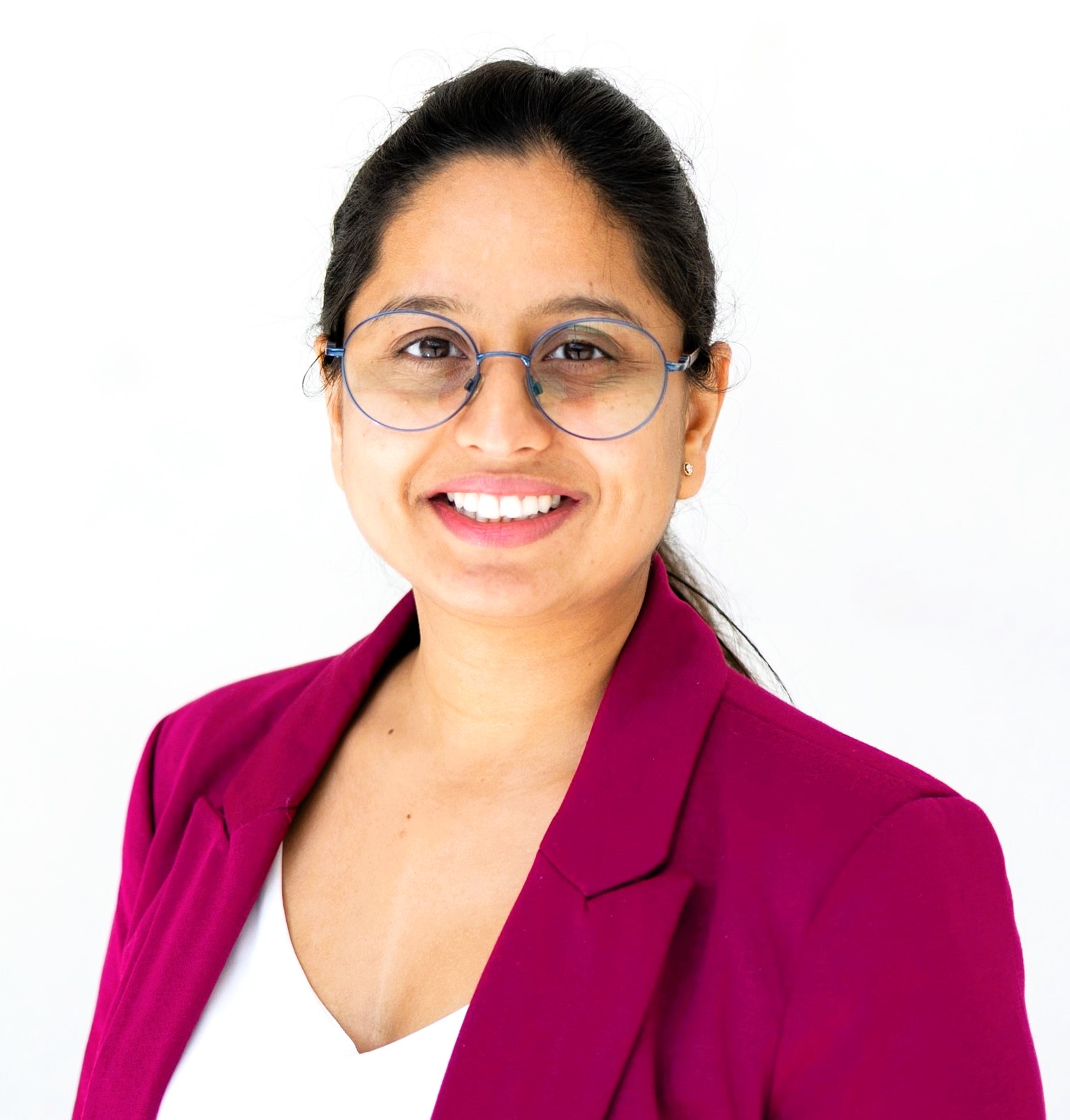 Headshot of Ila Mishra in a pink suit jacket