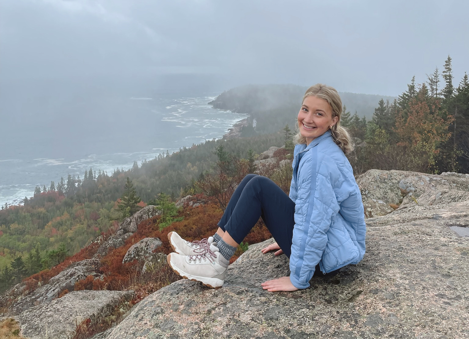 Allie Herron sitting at a view over a hiking trail.