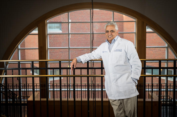Jay Avasarala posed against a railing in front of an arched window.