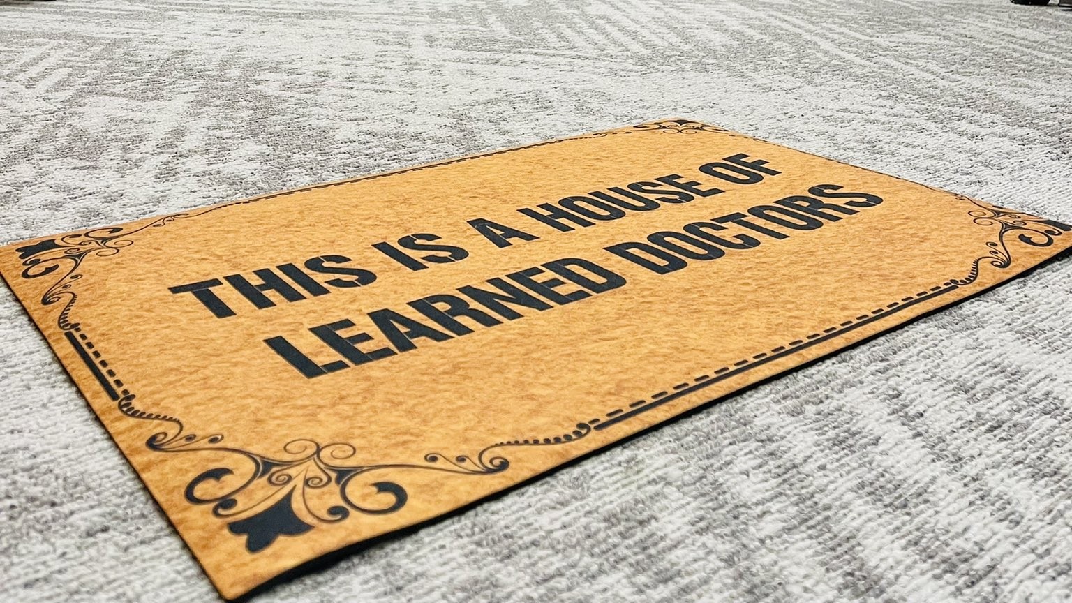floor mat with text "this is a house of learned doctors"