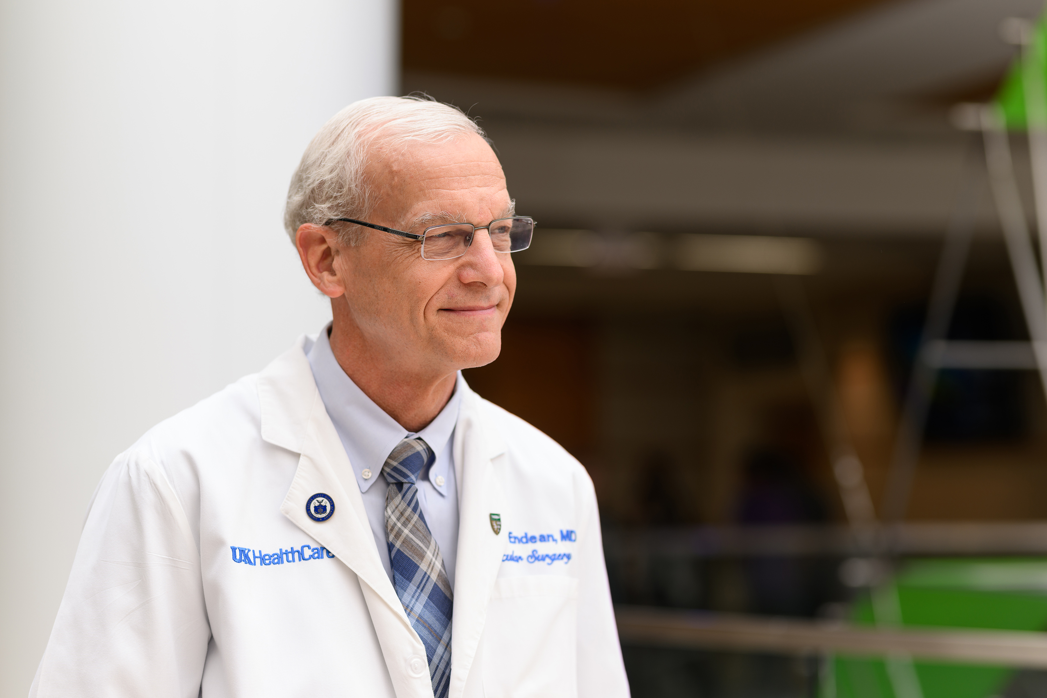 Dr. Rick Endean is  in his UK surgery white coat looking away to the right of the camera with a genial smile.