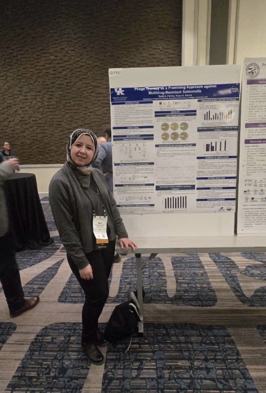 Nada Abdelkader standing beside her scientific poster, “Phage Therapy is a Promising Approach against Multidrug-Resistant Salmonella,” at a conference poster session.