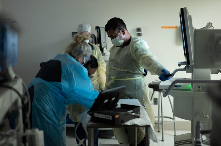 Clinical team performs a patient procedure in a hospital treatment room.
