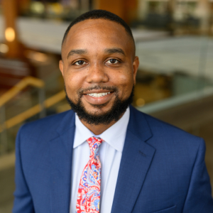 Headshot of Justin Xavier Moore in a blue suit