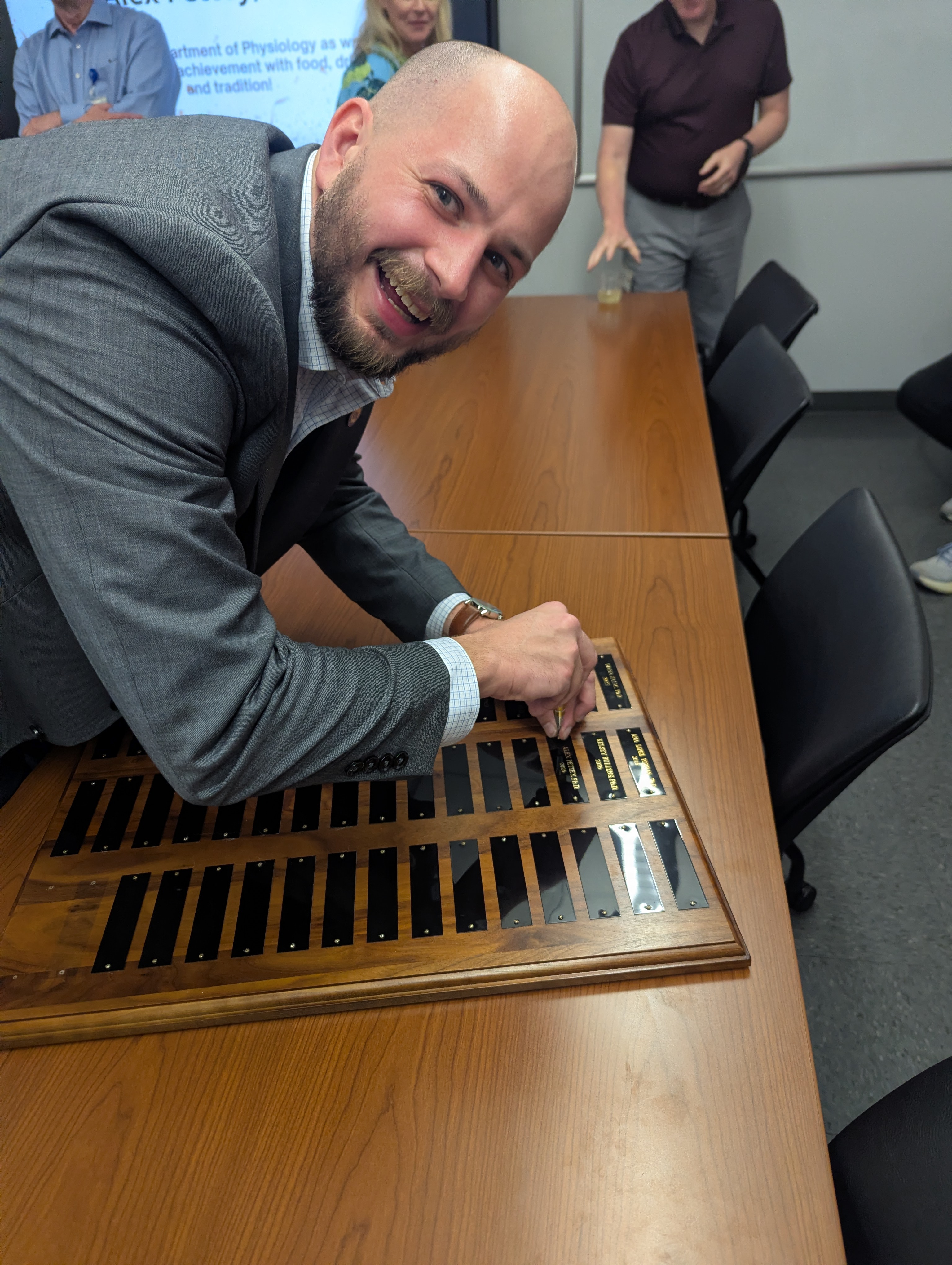 Alex Pettey adds his name to the plaque of graduates.