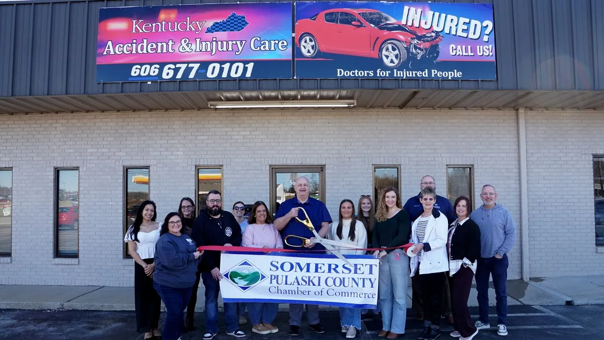A group of people pose for a ribbon-cutting ceremony in front of Kentucky Accident and Injury Care