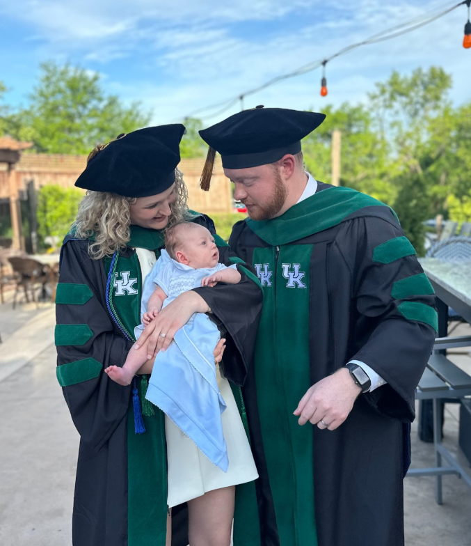Abigail and Jason Hurt pose in graduation regalia with newborn son, Griffin