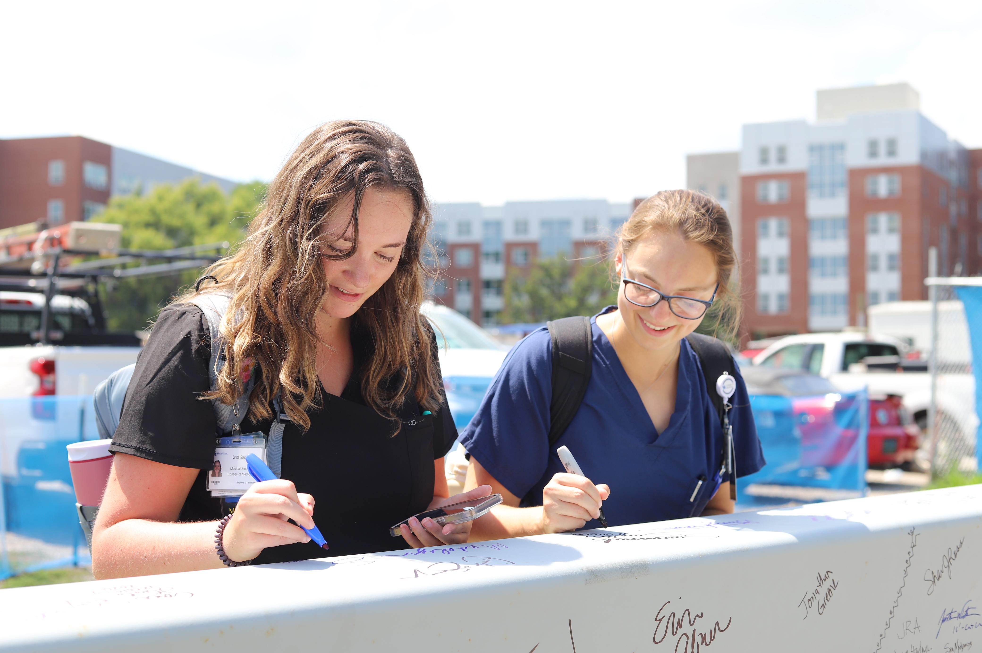  Faculty, staff, learners, and alumni signing a ceremonial beam