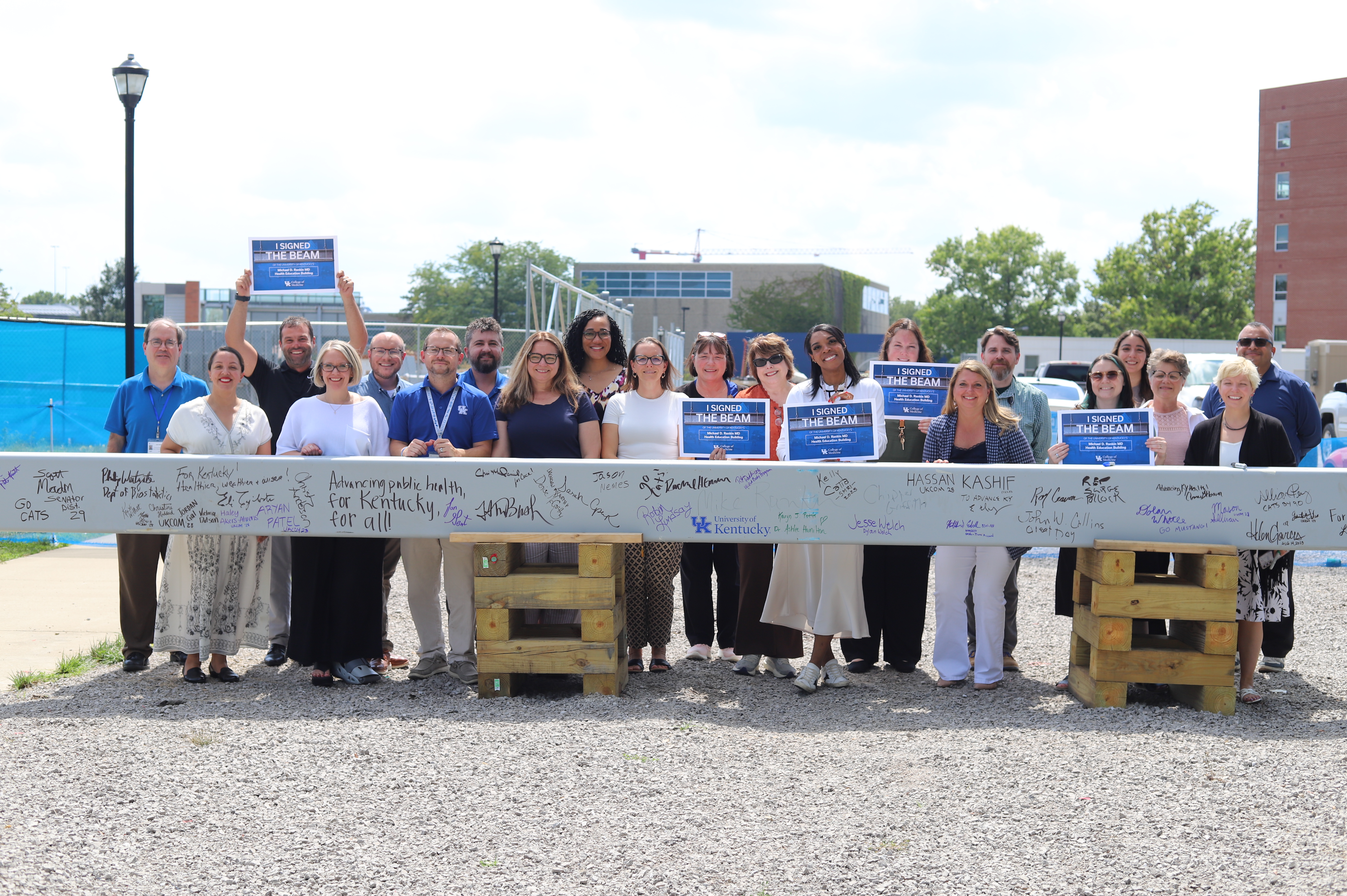  Faculty, staff, learners, and alumni signing a ceremonial beam