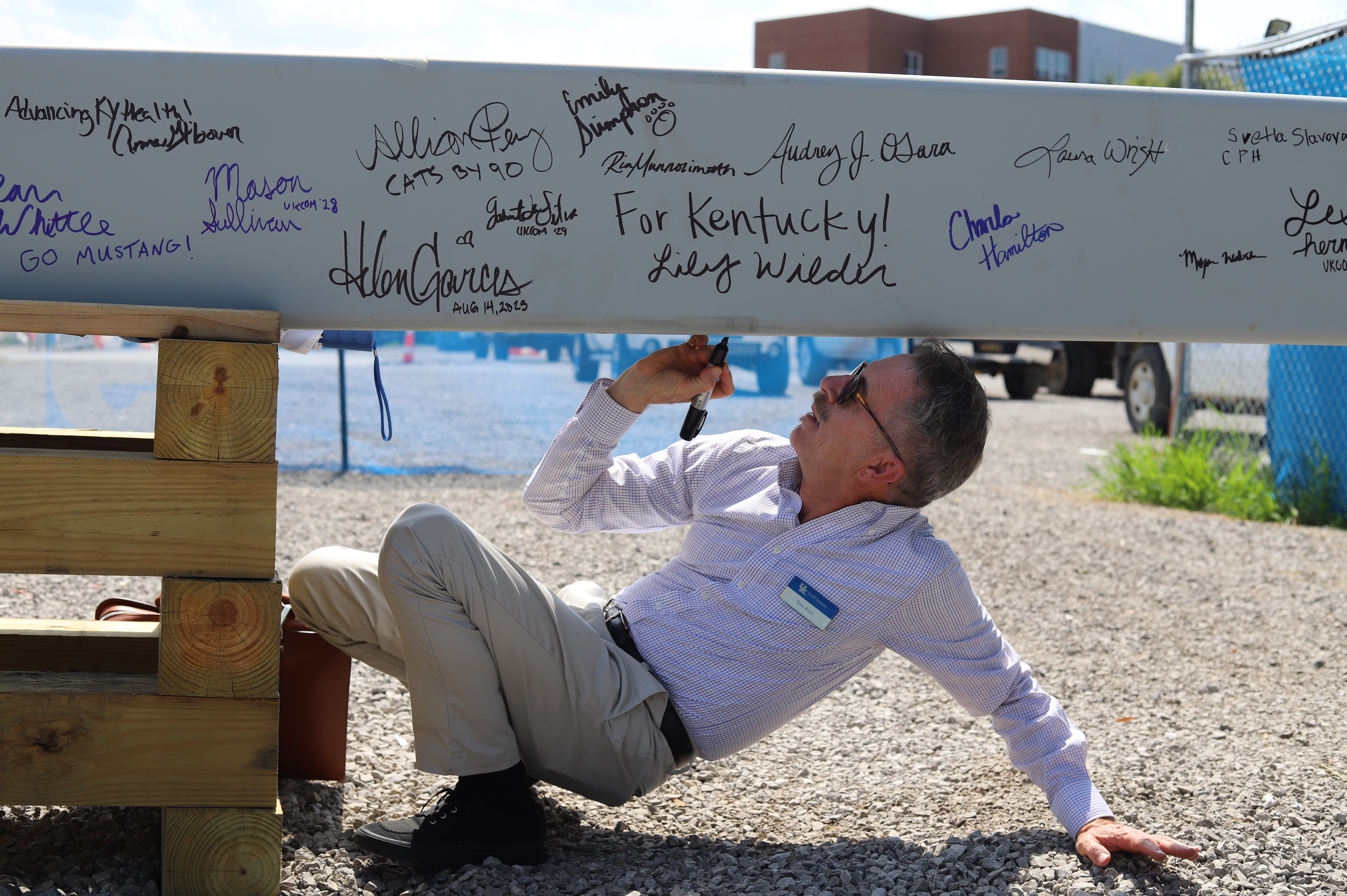  Faculty, staff, learners, and alumni signing a ceremonial beam