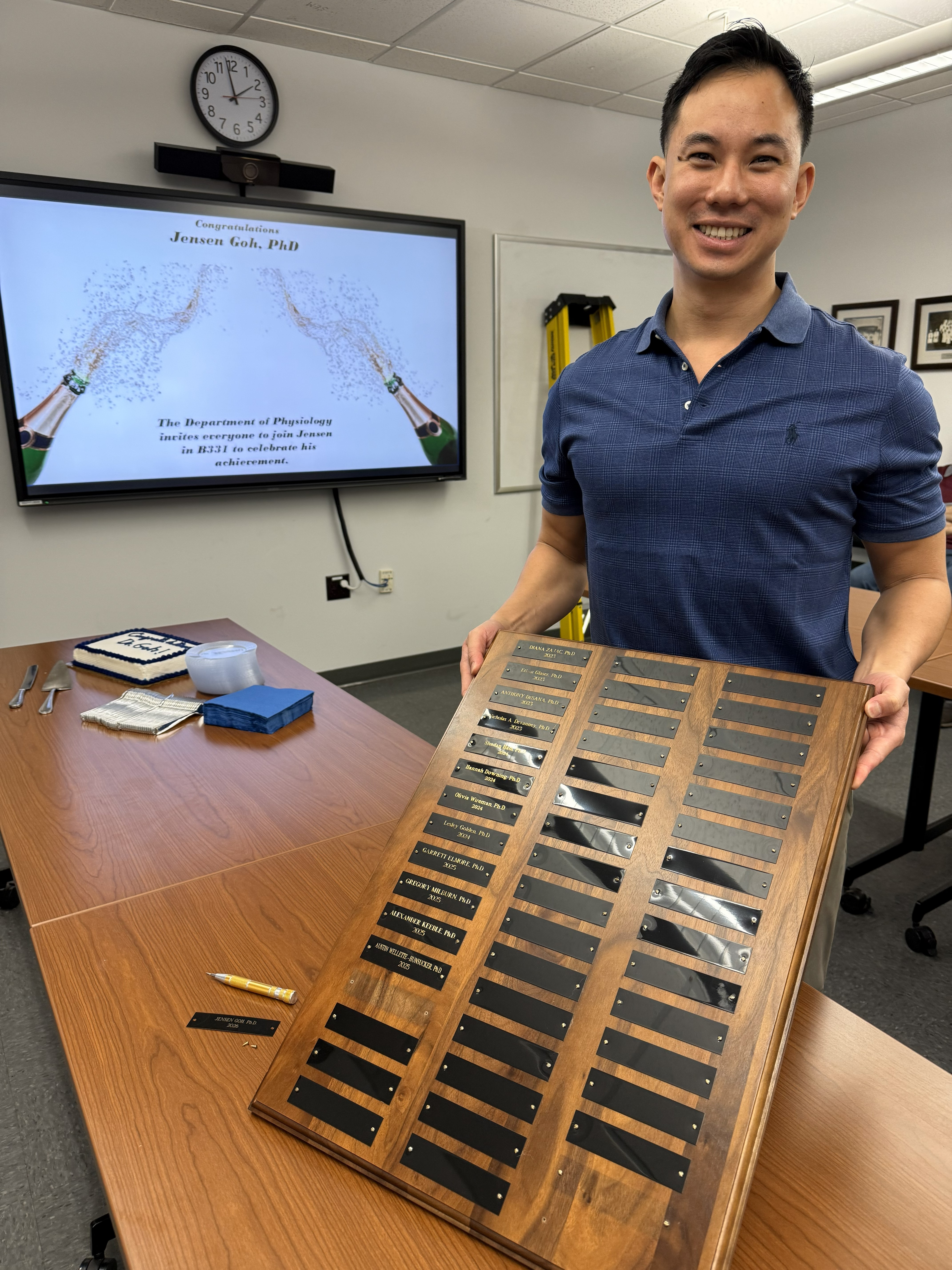 Jensen Goh holds the plaque adding his name to the list of PhDs. 