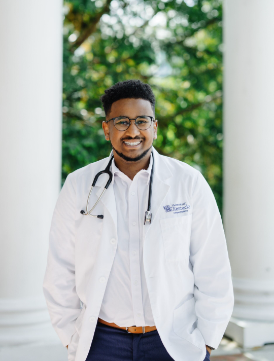 Kidus wears his white coat, with a stethoscope around his neck.