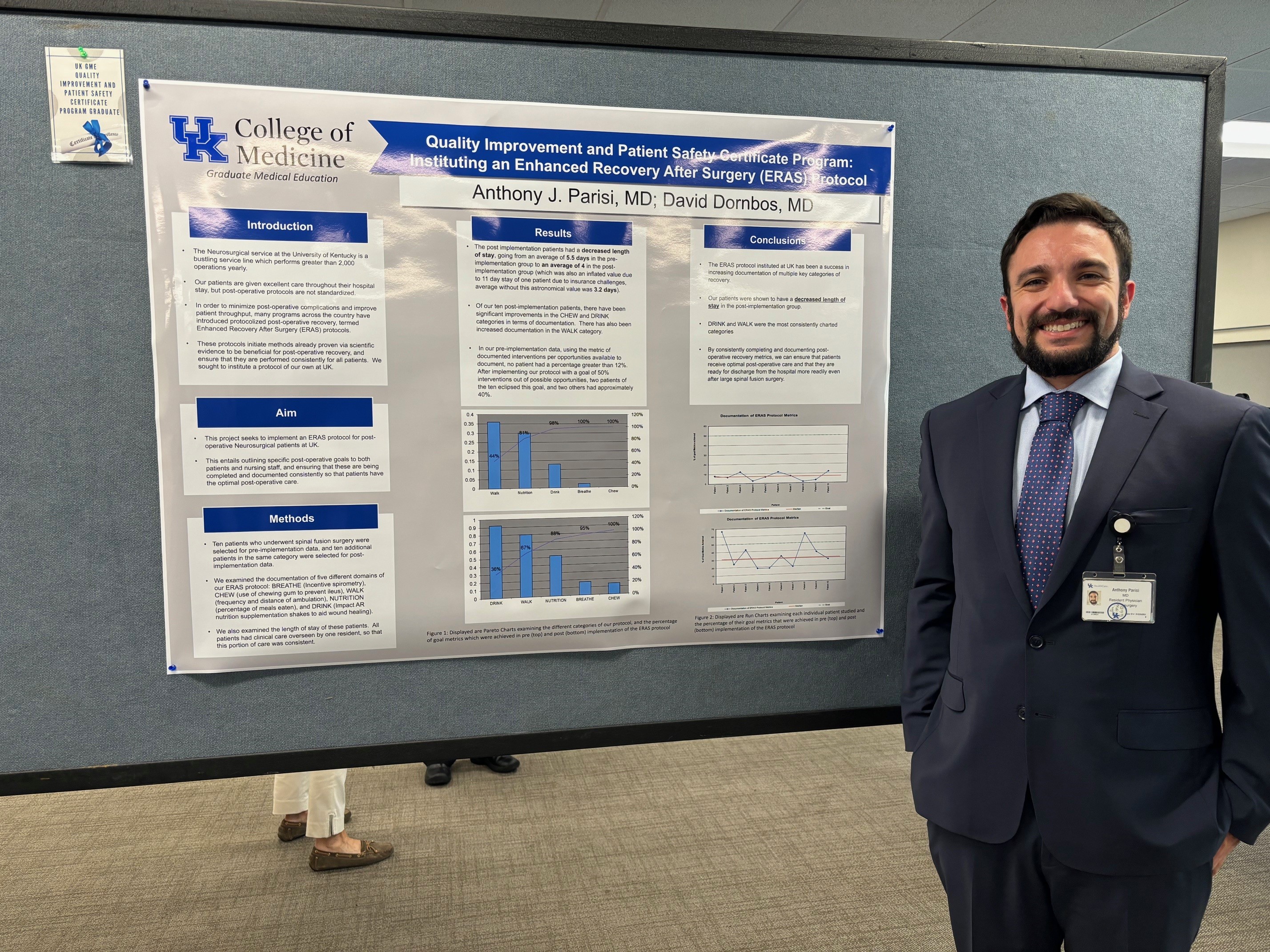 Resident stands in front of poster at GME poster presentation