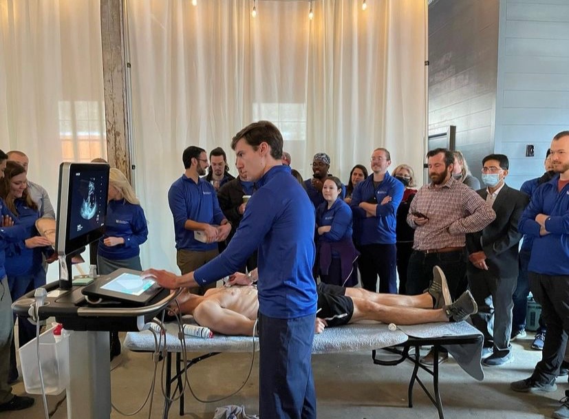 UK resident completing some sort of scan on volunteer; crowd watching