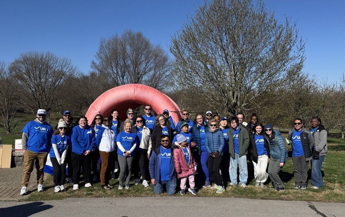 A large group of people stand in front of an inflatable colon, smiling for a photo.