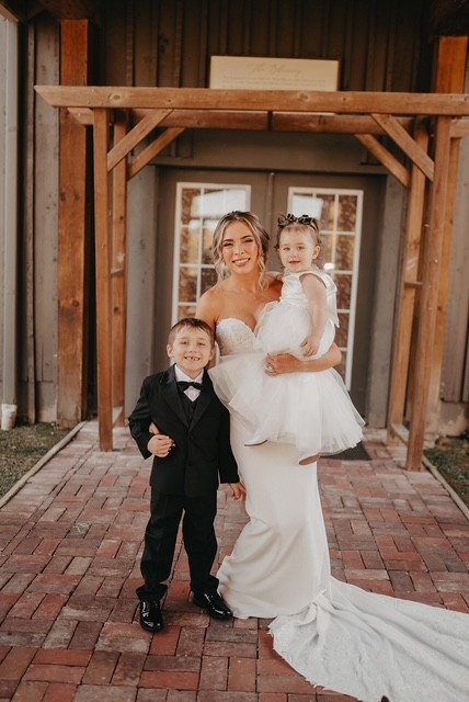Reagan Stafford in wedding dress posed with two children