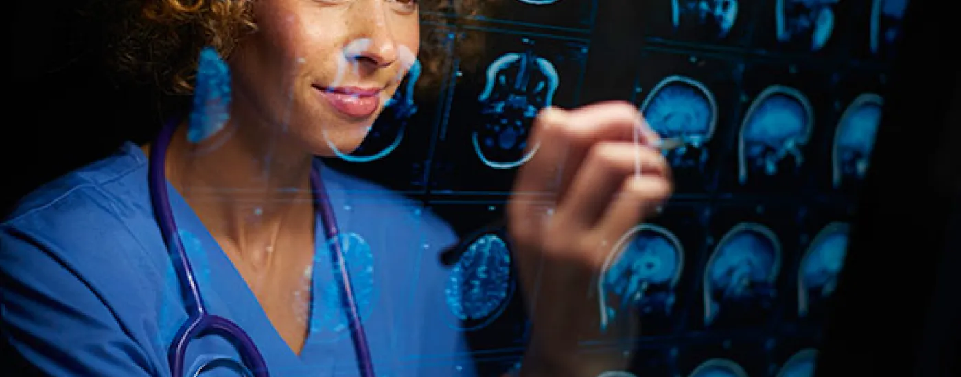 medical provider writing on a clear screen with images of human brain