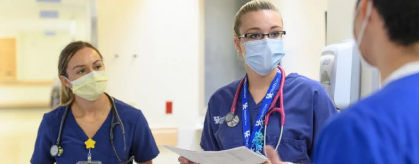 Three residents wearing masks and interacting in the hospital hallway