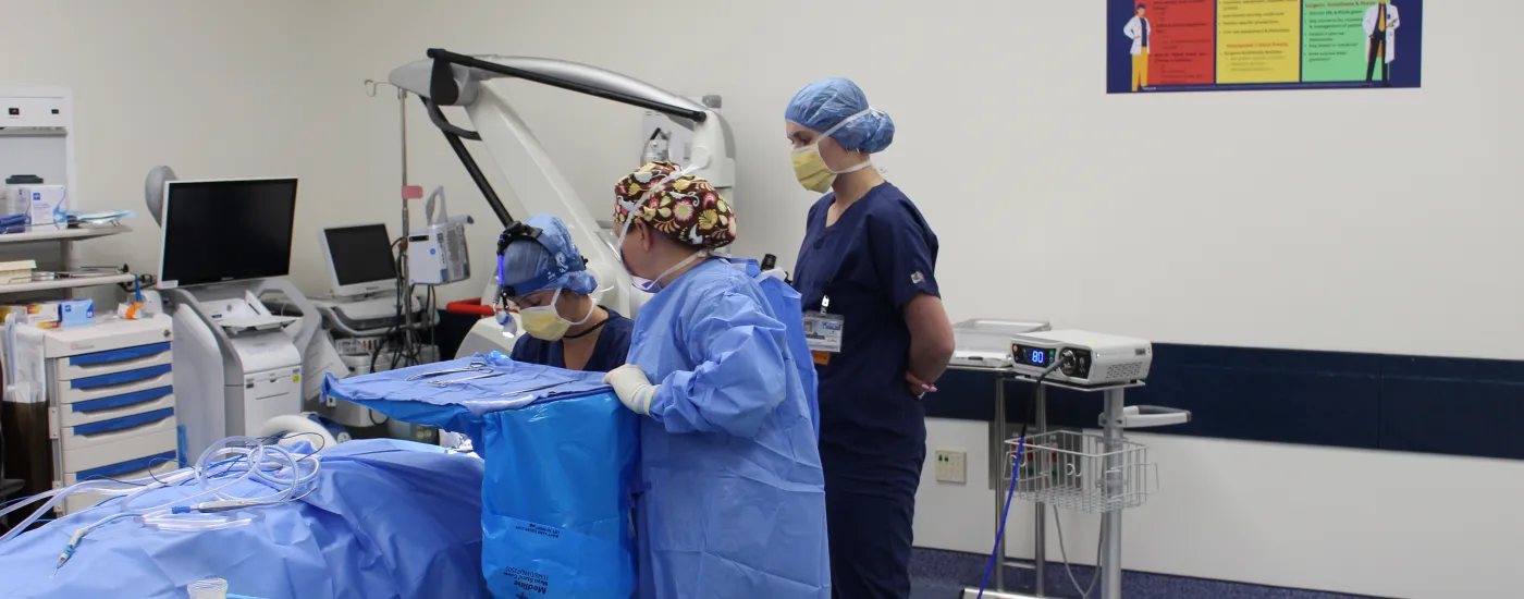 A picture of otolaryngologists in the OR conducting surgery with a student observer watching.