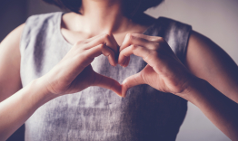 woman holding her hands up making a heart shape
