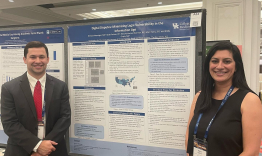 Dr. Wessinger and Dr Gupta standing in front of a blue and white medical poster.