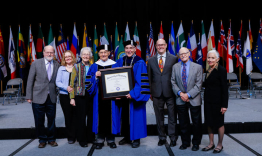 John Rosenberg and UK President Eli Capilouto hold Rosenberg's honorary degree, with Rosenberg's family and friends.