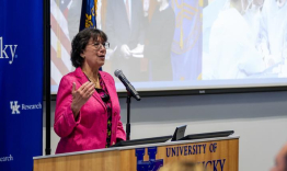 Monica Bertagnolli at a podium, addressing a University of Kentucky audience. 