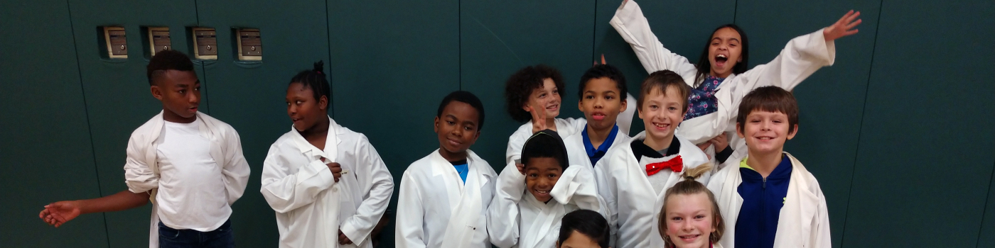 Students wearing lab coats at an outreach program.